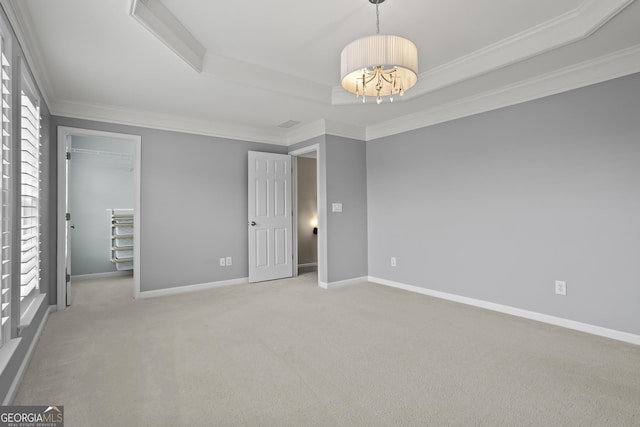 unfurnished bedroom featuring baseboards, ornamental molding, carpet flooring, an inviting chandelier, and a raised ceiling