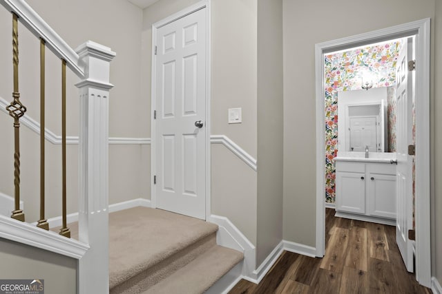 interior space with dark wood-type flooring, stairway, baseboards, and a sink