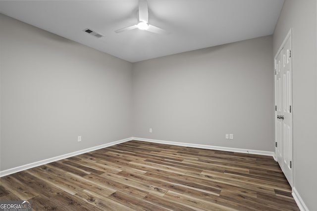 empty room with baseboards, dark wood-style floors, visible vents, and ceiling fan