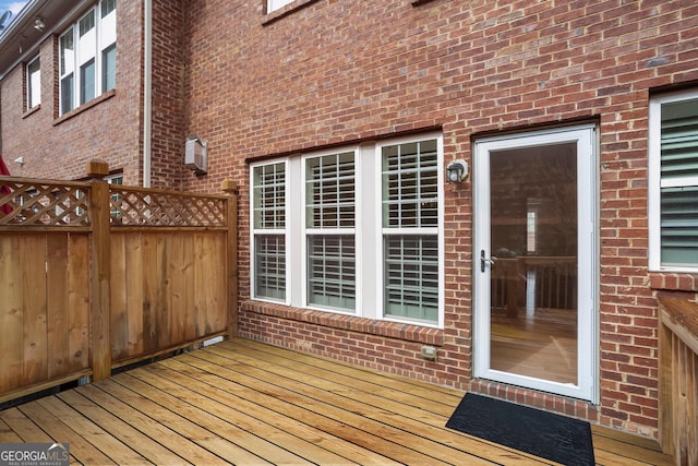 wooden terrace with an AC wall unit and fence