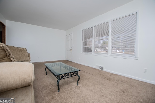 carpeted living area featuring visible vents and baseboards