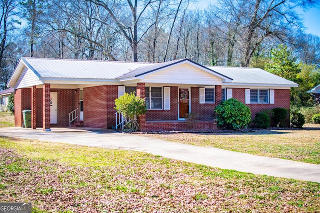 ranch-style house with metal roof, a front yard, brick siding, and driveway