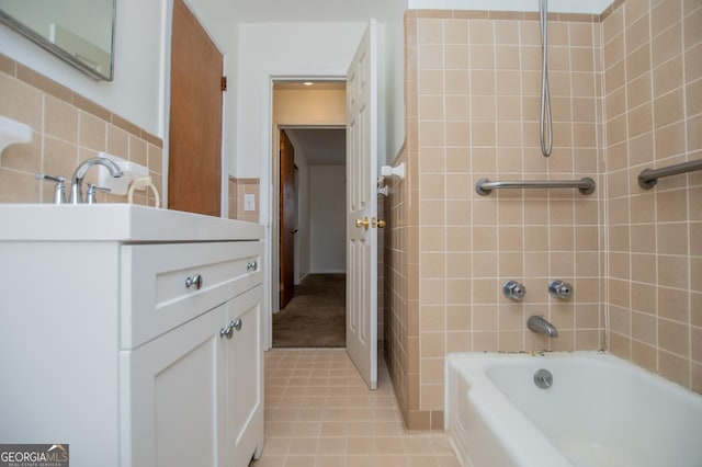 bathroom with vanity, tile patterned floors, washtub / shower combination, and tile walls