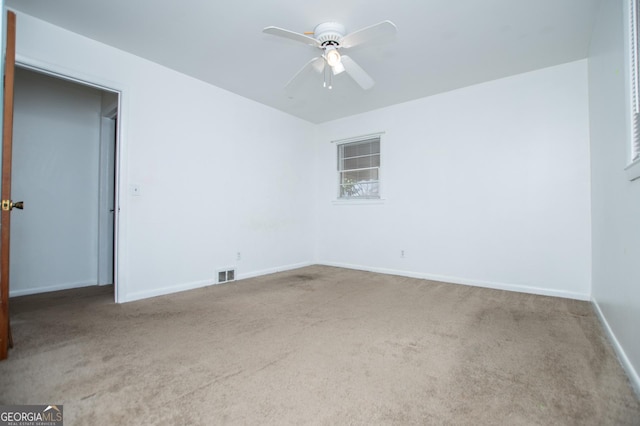 unfurnished room featuring visible vents, carpet flooring, baseboards, and a ceiling fan