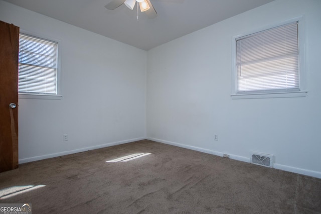 spare room featuring carpet flooring, baseboards, visible vents, and a ceiling fan