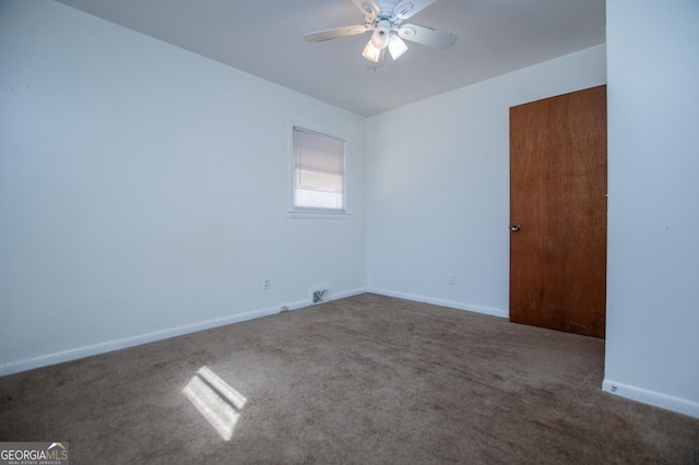 carpeted spare room with visible vents, baseboards, and ceiling fan