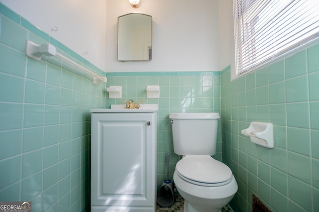 bathroom with vanity, tile walls, toilet, and a wainscoted wall