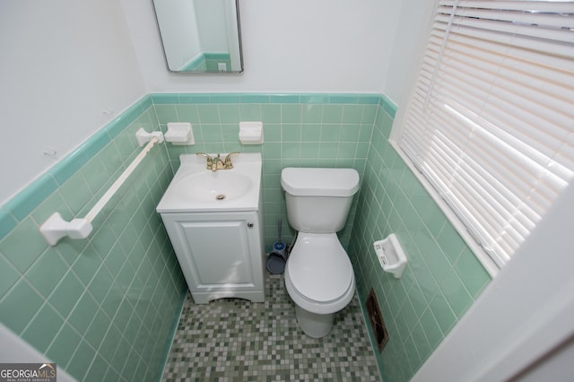 bathroom featuring toilet, tile walls, wainscoting, and vanity