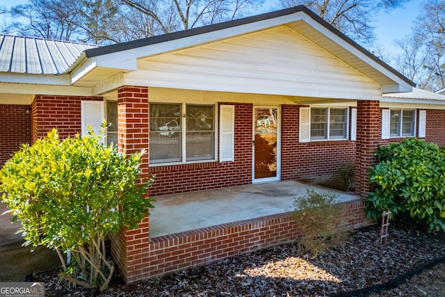 view of front of home featuring metal roof and brick siding