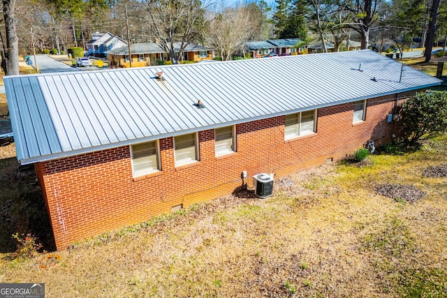 view of property exterior with brick siding, crawl space, metal roof, and central AC