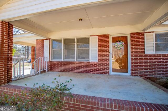 property entrance with a patio area and brick siding