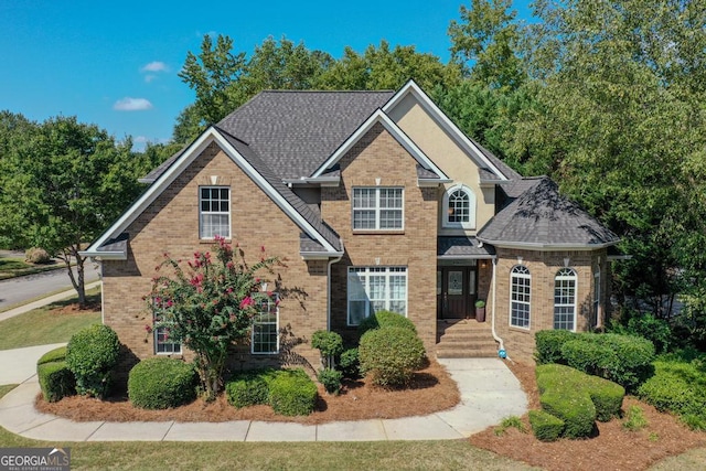 view of front of house featuring brick siding and roof with shingles