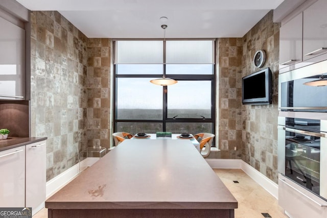 kitchen featuring tile walls, white cabinets, and pendant lighting