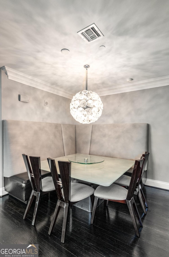 dining room featuring dark wood-style floors, visible vents, crown molding, and baseboards