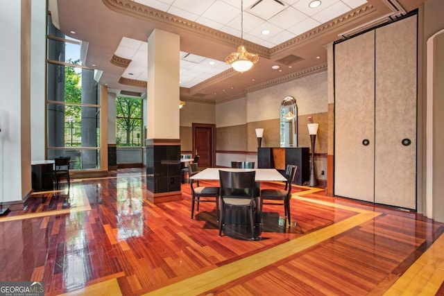 dining space with visible vents, hardwood / wood-style flooring, a towering ceiling, and ornamental molding