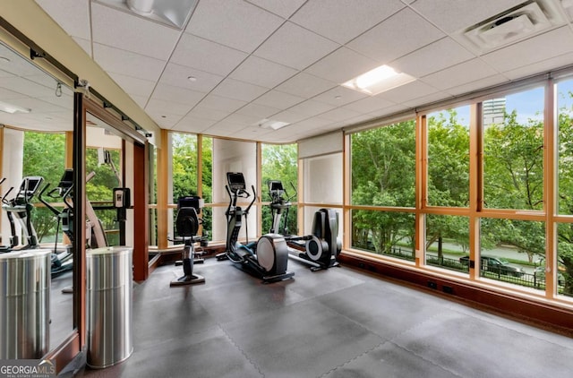 exercise room with visible vents, a drop ceiling, and expansive windows