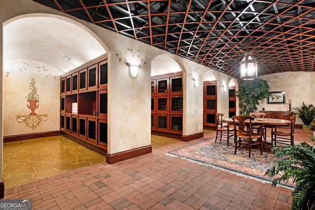 wine cellar with vaulted ceiling, brick floor, and baseboards