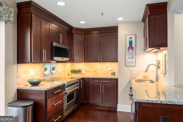 kitchen featuring tasteful backsplash, light stone counters, recessed lighting, appliances with stainless steel finishes, and a sink