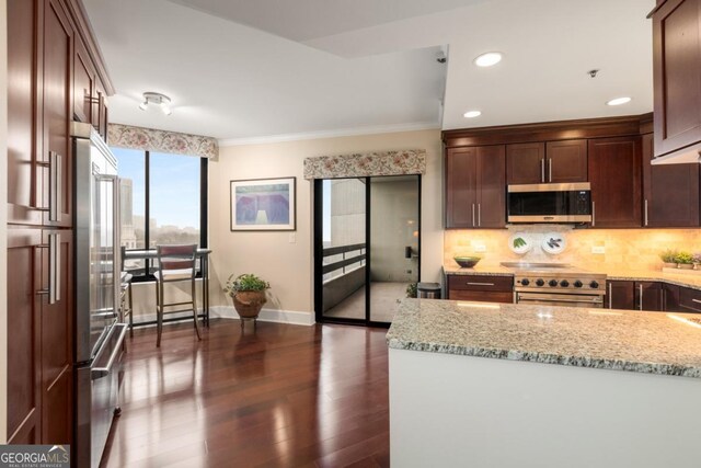 kitchen featuring light stone counters, decorative backsplash, baseboards, and appliances with stainless steel finishes