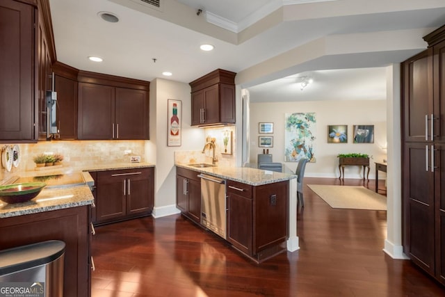 kitchen with tasteful backsplash, light stone countertops, appliances with stainless steel finishes, a peninsula, and a sink