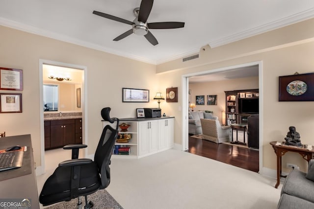 carpeted home office featuring crown molding, visible vents, and ceiling fan