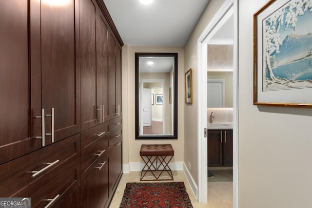 hall with light tile patterned floors, baseboards, and a sink