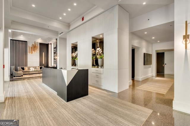 interior space with granite finish floor, recessed lighting, a towering ceiling, and ornamental molding