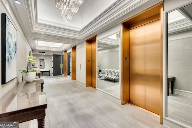 corridor with elevator, a raised ceiling, an inviting chandelier, and ornamental molding