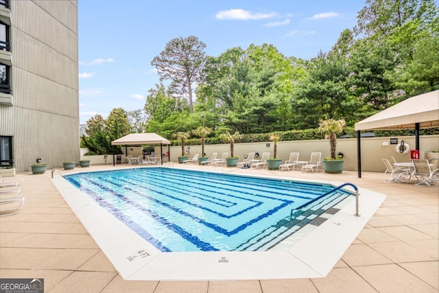 community pool with a patio and fence