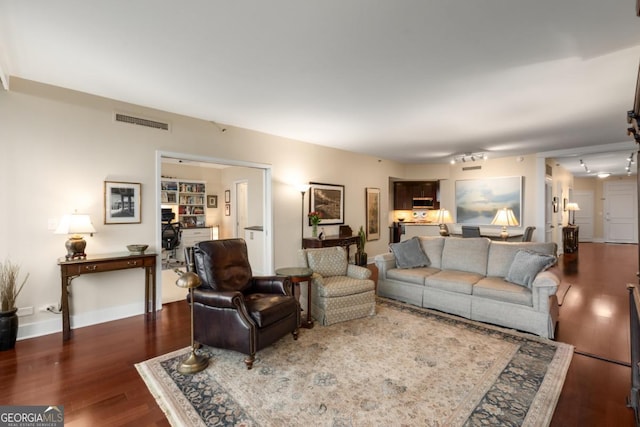 living area with visible vents, baseboards, and wood finished floors