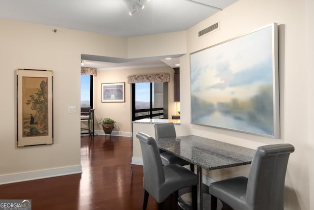 dining area featuring dark wood finished floors, visible vents, and baseboards