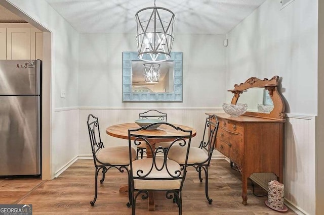 dining space featuring a wainscoted wall, wood finished floors, and a chandelier