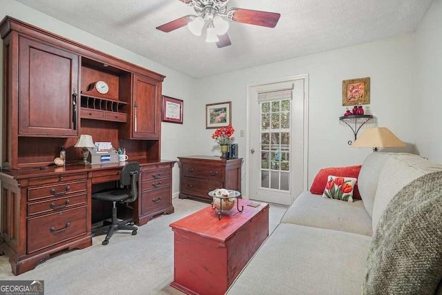 office space featuring a textured ceiling, ceiling fan, and light carpet