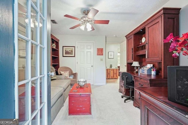 office space with ceiling fan, a textured ceiling, visible vents, and light carpet