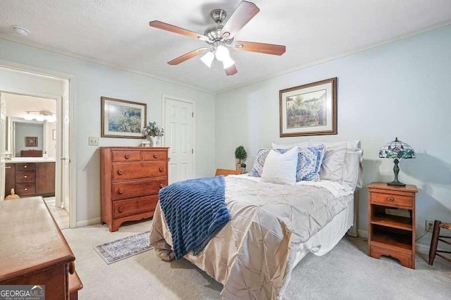 bedroom featuring baseboards, ensuite bath, ceiling fan, crown molding, and light colored carpet