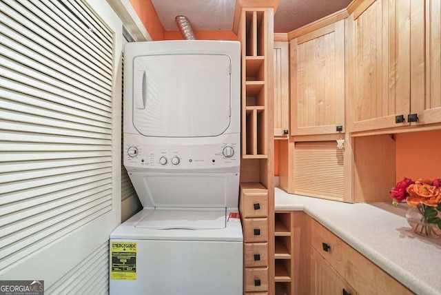 washroom with cabinet space and stacked washer / drying machine