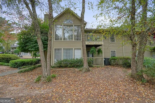 view of front of property featuring a balcony, central AC unit, and a chimney