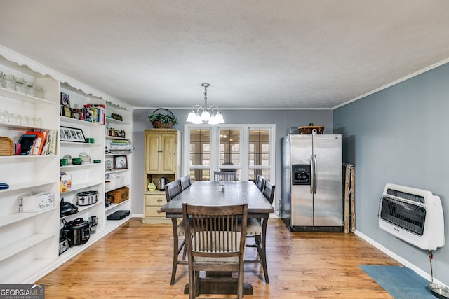 dining room featuring a notable chandelier, heating unit, crown molding, and light wood finished floors