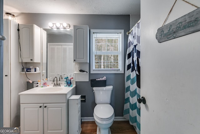 bathroom featuring vanity, wood finished floors, baseboards, a textured ceiling, and toilet