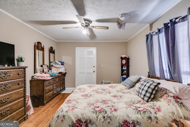 bedroom featuring light wood-style flooring, a textured ceiling, ceiling fan, and ornamental molding