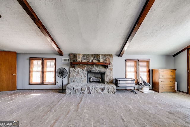 unfurnished living room with beam ceiling, a stone fireplace, and a textured ceiling