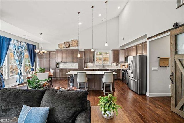 living area with a high ceiling, baseboards, dark wood-style flooring, and a chandelier