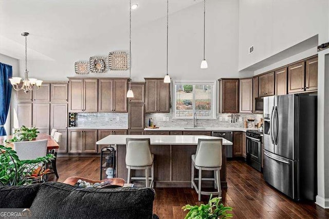 kitchen featuring a kitchen island, a sink, stainless steel appliances, light countertops, and a kitchen breakfast bar