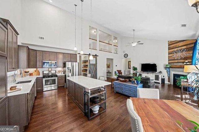 kitchen featuring a kitchen island, dark brown cabinetry, light countertops, stainless steel appliances, and a sink