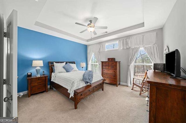 bedroom featuring carpet flooring, multiple windows, baseboards, and a tray ceiling