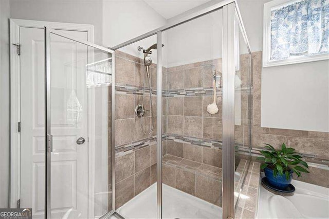 bathroom with a stall shower and a tub to relax in