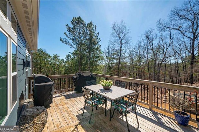 wooden terrace featuring outdoor dining space and grilling area