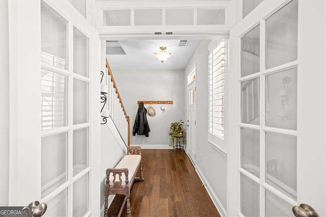 hall with visible vents, baseboards, wood finished floors, and stairs