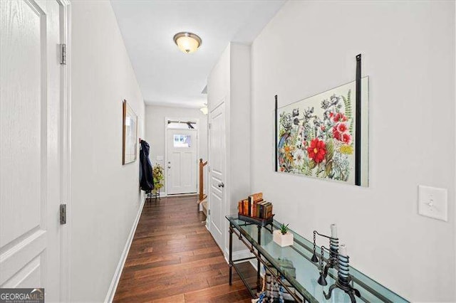 hall featuring dark wood-type flooring and baseboards