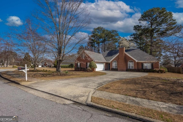 view of front of house featuring a garage, brick siding, a chimney, and driveway